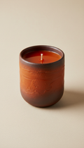A product shot featuring a deep orange soy candle from Artisan Glow, perfectly centered on a minimalistic background. The...
