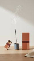 Designer matchbox and matte textured packaging in Urban Terracotta and Muted Rose., Hero angle is 3/4 frontal at table-top...